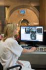 Retrato de una doctora examinando una resonancia magnética cerebral en una computadora - foto de stock