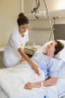 Enfermera atendiendo paciente en cama de hospital - foto de stock
