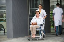 Жінка-лікар штовхає пацієнта сидячи в кріслі — стокове фото