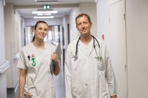 Doctor and female nurse smiling while walking in corridor of hospital — Stock Photo
