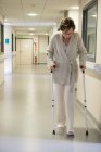 Paciente femenina caminando con ayuda de muletas en el hospital - foto de stock