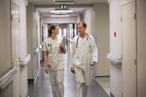 Врач и медсестра, идущие по коридору больницы — стоковое фото
