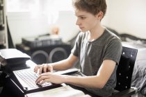 Хлопчик-підліток друкує на ноутбуці вдома — стокове фото