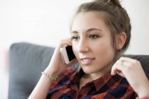 Adolescente falando no telefone no sofá em casa — Fotografia de Stock