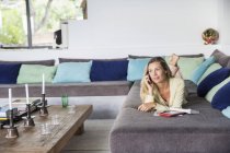 Entspannte Frau liegt auf Sofa und telefoniert im Hotel — Stockfoto