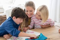 Madre e figli che fanno i compiti sul tavolo — Foto stock