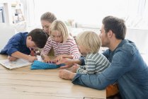 Genitori e bambini che fanno i compiti a casa a tavola in legno — Foto stock