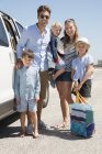 Счастливая молодая семья стоит у машины на каникулах — стоковое фото