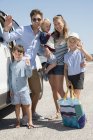 Feliz familia joven de pie en el coche de vacaciones - foto de stock