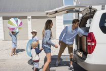Молодая семья упаковывает автомобиль с пляжными шестеренками для отдыха — стоковое фото