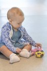 Close-up de menina brincando com brinquedo no chão em casa — Fotografia de Stock
