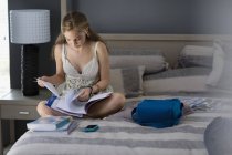 Teenager-Mädchen sitzt zu Hause auf Bett und studiert — Stockfoto