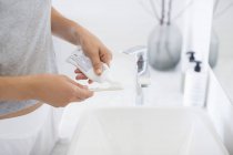 Mani femminili che spremono il dentifricio da tubo su spazzolino da denti — Foto stock