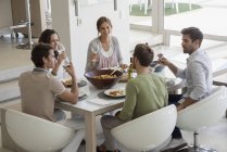 Group of happy friends having lunch at dining table — Stock Photo