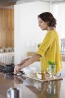 Donna sorridente che prepara tisane in cucina — Foto stock