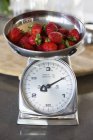 Fresh red strawberries on weighing scale at a kitchen counter — Stock Photo