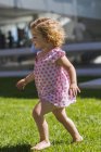 Menina bonito andando no gramado verde no verão ao ar livre — Fotografia de Stock