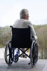 Homem sênior em cadeira de rodas relaxante ao ar livre — Fotografia de Stock