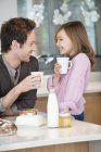 Homem bebendo chá com filha feliz na cozinha — Fotografia de Stock