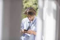 Молода людина текстові повідомлення зі смартфоном на відкритому повітрі — стокове фото