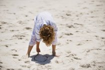 Мальчик играет с песком на солнечном пляже — стоковое фото