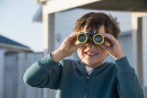 Bambino felice guardando attraverso binocoli all'aperto — Foto stock