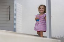 Joyeux bébé fille tenant bouteille d'eau sur le porche — Photo de stock