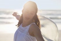 Glückliche junge Frau posiert am Strand im Sonnenlicht — Stockfoto