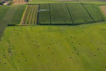 Francia, Dordogna, veduta aerea di un campo verde e pagliai in primo piano, un campo di grano sullo sfondo — Foto stock
