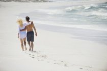 Vista posteriore di abbracciare coppia a piedi sulla spiaggia — Foto stock