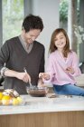 Man stirring a mixture in bowl with daughter — Stock Photo
