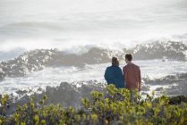 Casal feliz olhando para o mar ondulado na praia — Fotografia de Stock