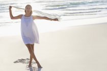 Portrait of young woman enjoying standing on beach with pareo — Stock Photo