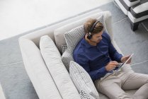 Junger Mann sitzt auf Couch und benutzt ein digitales Tablet — Stockfoto