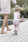 Rear view of little boy walking with mother at poolside — Stock Photo