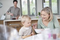 Donna che alimenta la colazione piccolo figlio in cucina — Foto stock