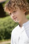 Close-up de menino sorridente com cabelo encaracolado dia sonhando na natureza — Fotografia de Stock