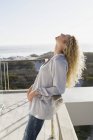 Mitte erwachsene Frau lehnt im Urlaub an Balkon an Küste — Stockfoto