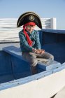 Пиратский мальчик держит монеты на лодке — стоковое фото