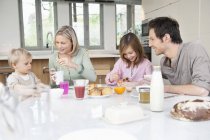 Familia feliz divirtiéndose en la mesa del desayuno - foto de stock
