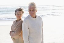 Расслабленная вдумчивая старшая пара, стоящая на пляже вместе — стоковое фото