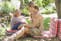 Mother and little girl looking at each other and talking on grass outdoors — Stock Photo