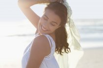 Jeune femme ludique posant sur la plage avec pareo — Photo de stock