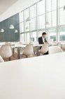 Geschäftsmann sitzt in moderner Cafeteria und nutzt Laptop — Stockfoto