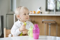 Cute baby boy sitting at dining table and looking away — Stock Photo