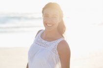 Porträt einer lächelnden jungen Frau am Strand im Gegenlicht — Stockfoto