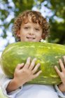 Gros plan d'un garçon souriant tenant la pastèque à l'extérieur — Photo de stock