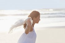 Relaxed young woman walking on beach with pareo — Stock Photo