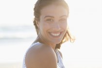 Porträt einer lächelnden jungen Frau am sonnigen Strand — Stockfoto