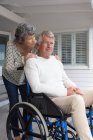 Hombre mayor en silla de ruedas con su esposa en el porche - foto de stock